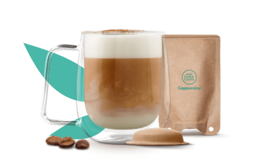 Caneca com cappuccino ao lado de uma cápsula e saqueta à base de papel